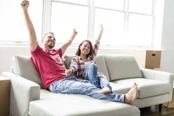 Casal sentado juntos no sofá em casa feliz em se mudar de casa — Fotografia de Stock