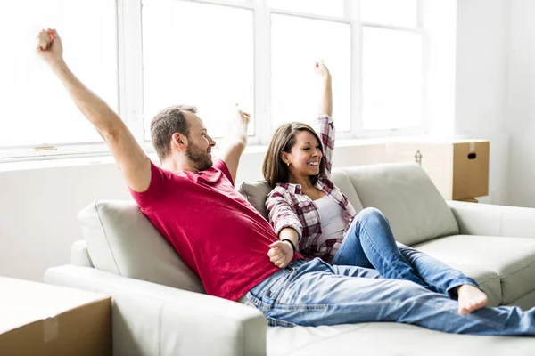 Casal sentado juntos no sofá em casa feliz em se mudar de casa — Fotografia de Stock