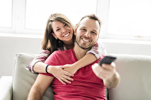 Birlikte uzaktan ile evde koltukta oturan çift tv kontrol — Stok fotoğraf