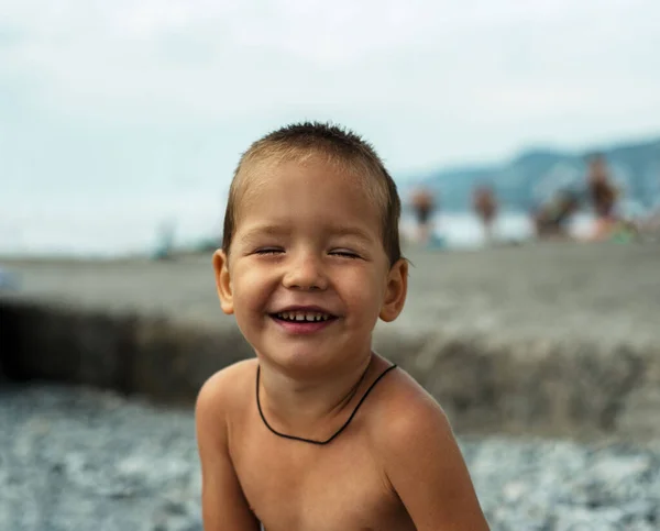 Niño riéndose con los ojos cerrados en la playa — Foto de Stock