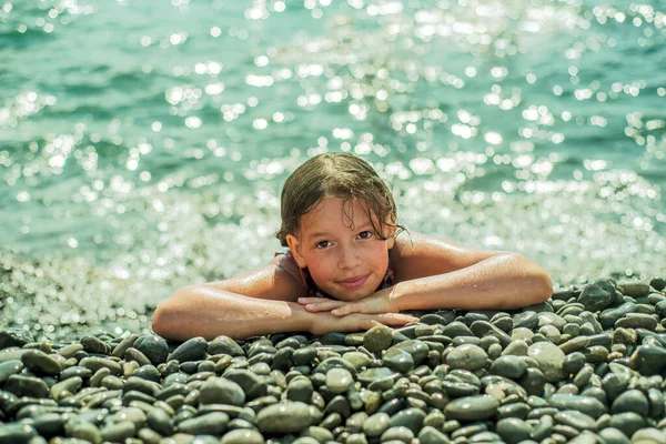 Adolescente acostada en una playa de guijarros con mar turquesa en el fondo — Foto de Stock