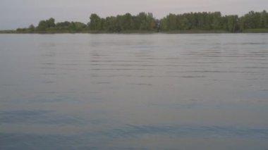 Gün batımında gri nehir yüzeyindeki dalgaların dokusu, gün batımında nehir dalgaları sakince kıyıya doğru akıyor.