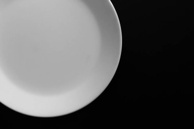 Siyah ahşap masada boş beyaz tabak. Mutfak aletleri kapatın.