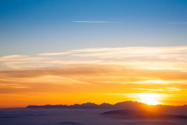 Mountain silhouette at sundown from Italian Alps. Clouds background