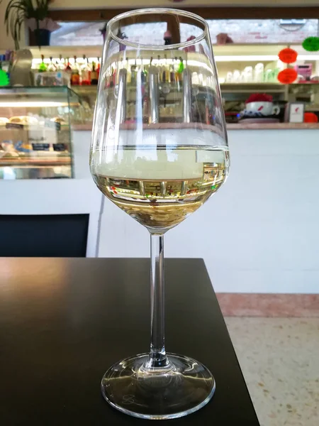 Glass of white wine close up with bar in background