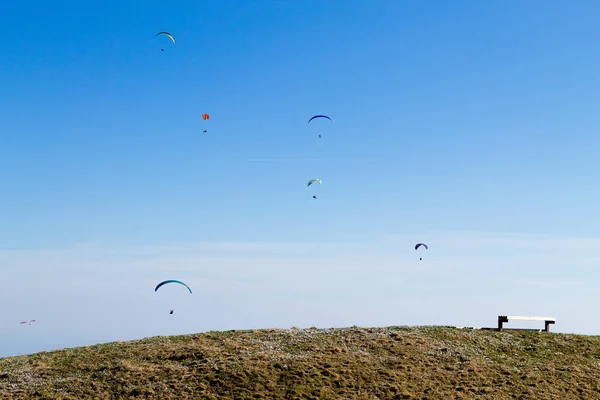 Paraglider på blå himmel med Tom bänk på förgrunden — Stockfoto