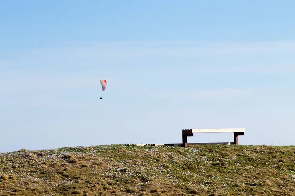 Paraglider på blå himmel med Tom bänk på förgrunden — Stockfoto