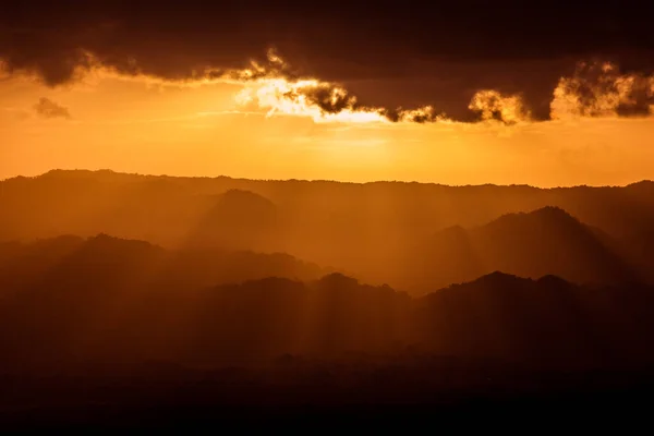 Sunlight rays through the mountains with bird silhouette at sunset in Miches, Dominican Republic