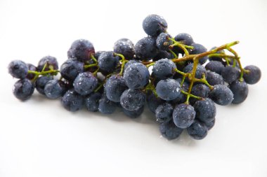 Siyah üzümler, beyaz arka planda yeşil yapraklı büyük taze meyveler