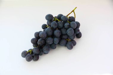 Siyah üzümler, beyaz arka planda yeşil yapraklı büyük taze meyveler