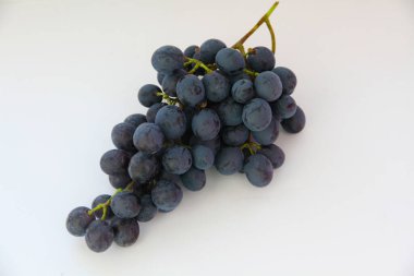 Siyah üzümler, beyaz arka planda yeşil yapraklı büyük taze meyveler