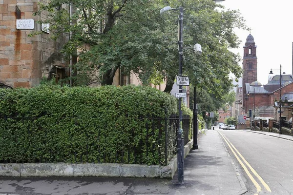 Glasgow İskoçya - 20 Ağustos 2017: Glasgow şehir merkezindeki Scott Caddesi yakınlarındaki bir yerleşim bölgesinde yeşil çit, ağaç, ev ve kilise kulesi bulunan boş sokaklar