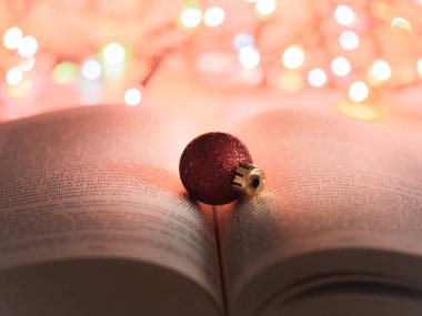 Kırmızı parlak ve parlak Noel süsleme ile arka planda renkli Noel ışıkları açık bir kitap üzerinde inanılmaz ayrıntı