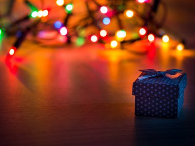 Şerit ve renkli Noel ışıkları arka planda küçük hediye
