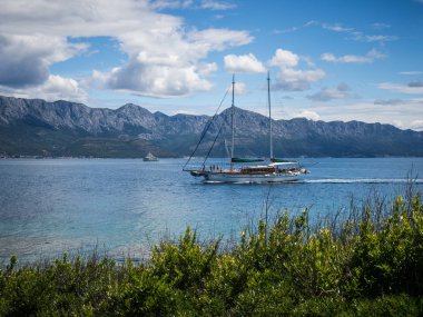 Yelkenli tekne bir kıyı Hvar Adası, Hırvatistan gün güneşli yaz, dağlar ve taze yeşil çim görünümünü geçen