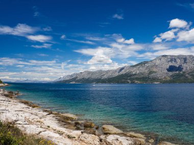 Hvar Adası, taze yeşil çimen, mavi gökyüzü ve dağlar ile Hırvatistan güzel kıyısında bir yol