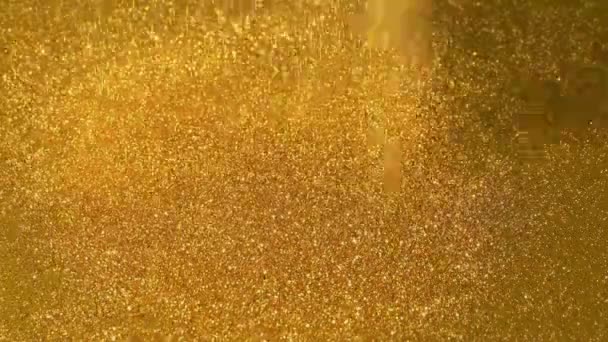 La poudre d'or étincelante verse sur la surface d'or 