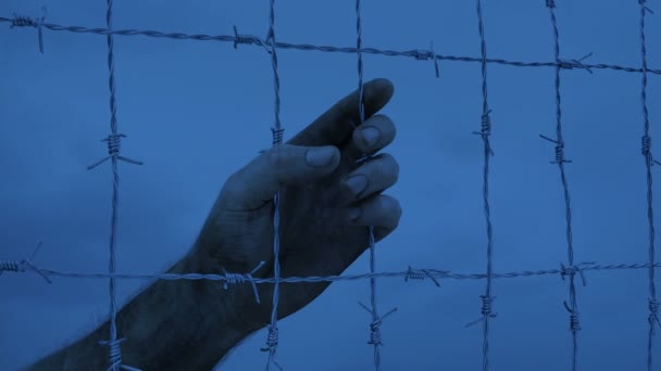 囚人は暗闇の中でフェンスを保持します — ストック動画