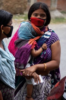 Dehradun, Uttarakhand / Hindistan - 15 Ağustos 2020: Kadınlar çocuğuyla yüz maskesi takıyor, sosyal mesafeyi koruyorlar.