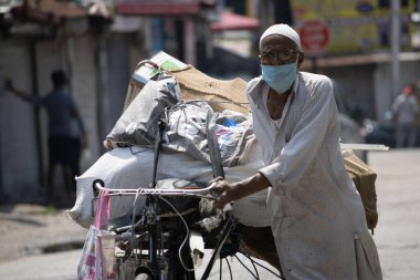 Dehradun, Uttarakhand / Hindistan - 15 Ağustos 2020: Yaşlı bir adam triportörünü yüz maskesi takarak çeker.  