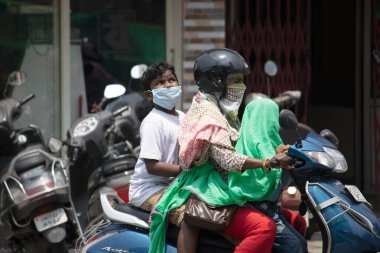 Dehradun, Uttarakhand / Hindistan - 15 Ağustos 2020: Anne ve kız çocuğu maske takıyor sosyal mesafeyi koruyor, kameraya bakıyor.