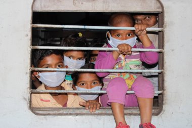 Dehradun, Uttarakhand / Hindistan - Ağustos 01: 2020: Pencereden bakan insanlar / çocuklar, işteki polisler, koronavirüs covid-19 nedeniyle maske ve PPE kiti takıyorlar.