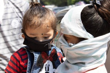 Dehradun, Uttarakhand / Hindistan - Eylül 06 2020: yüzünü çocuğuyla örten kadın.