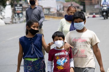 Dehradun, Uttarakhand / Hindistan - Eylül 06 2020: Yüz maskesi takan çocuklar yola çıkıyor