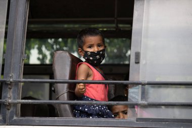 Dehradun, Uttarakhand / Hindistan - Eylül 08 2020: Otobüste maskeli şirin bir kız çocuğu.