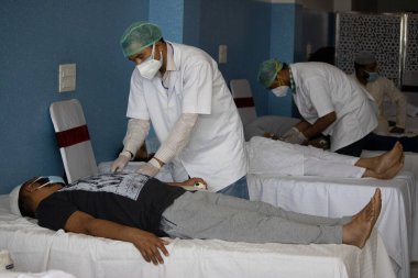 Dehradun, Uttarakhand / Hindistan - 10 Eylül 2020: Doktor yüz maskesi ve eldiven takan hastayı kontrol ediyor.
