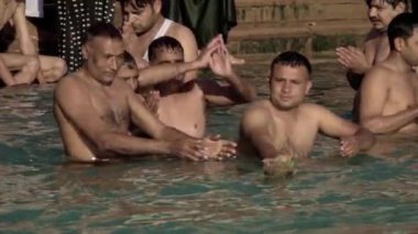 Seyyahların ayinsel banyo yaparken yavaş çekimleri ve Har Ki Pauri, Haridwar, Uttarakhand 'deki Ganga Nehri' nde yüzen mumlarla Tanrıça Ganj 'a (Ganga) dualarını sunmaları..