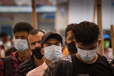 Tren istasyonunda yüz maskesi takan gençler resmi kayıt için bekliyorlar..