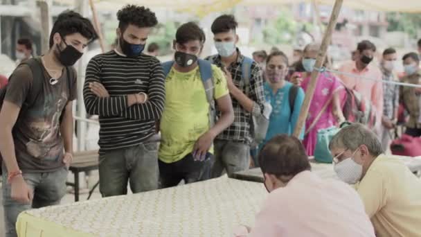 Regeringsambtenaar doet registratie van passagiers op een station, tijdens de corona pandemie in India — Stockvideo