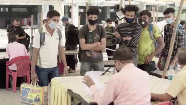 Regeringsambtenaar doet registratie van passagiers op een station, tijdens de corona pandemie in India — Stockvideo