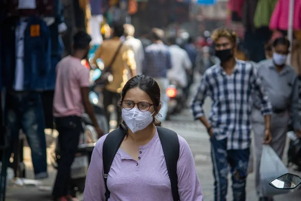 Eine Studentin mit Gesichtsmaske läuft in Indien über den Markt, eine Maske ist aufgrund der Coronaepidemie Pflicht. Stockfoto
