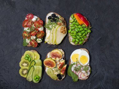 Farklı dolgularla bezenmiş Siyah arka planda izole edilmiş, üst manzara. Çeşitli dolgu seçenekleriyle birlikte kızarmış ekmek. Geleneksel İtalyan yaz iştahı. Kapat..