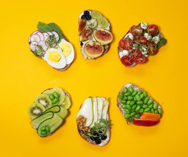 Farklı dolgularla bezenmiş Sarı arka planda, üst manzarada izole edilmiş. Çeşitli dolgu seçenekleriyle birlikte kızarmış ekmek. Geleneksel İtalyan yaz iştahı. Kapat.