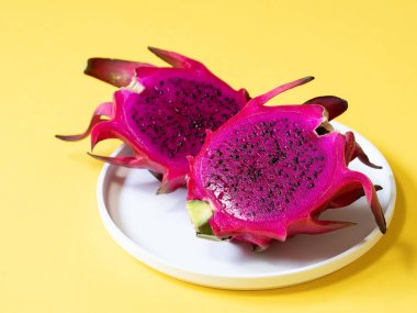 Sarı arka planda pembe pitahaya. Kapatın. Tropikal ejderha meyvesi tabakta canlı pembe renkler sergiliyor..