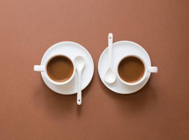 Kahverengi arka planda fotokopi alanı olan beyaz kahve fincanları. Küçük bardaklarda siyah espresso. Kahve konsepti. Üst görünüm.