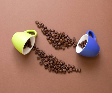 Kahverengi arkaplanda kahve çekirdekleri ve fotokopi alanı olan renkli kahve fincanları. Kahve konsepti. Üst görünüm.