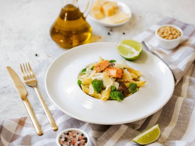 Somon, brokoli ve beyaz-gri arka planda pesto soslu makarna..