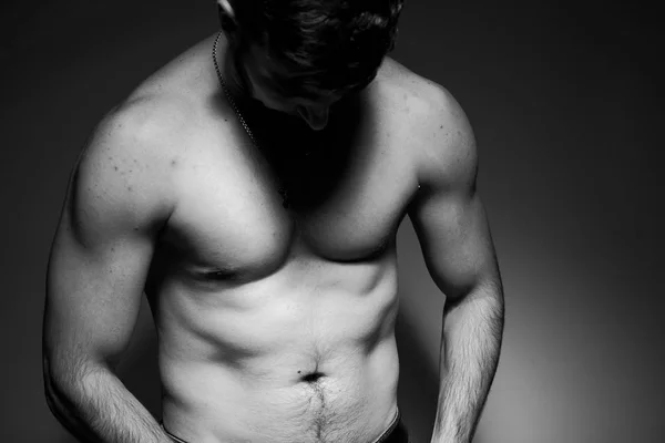 Black and white photo of a handsome and sporty guy close-up in studio