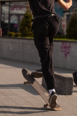 Şık giyinmiş gençler parkta kaykaya biniyorlar..