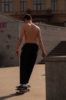 Şık giyinmiş gençler parkta kaykaya biniyorlar..