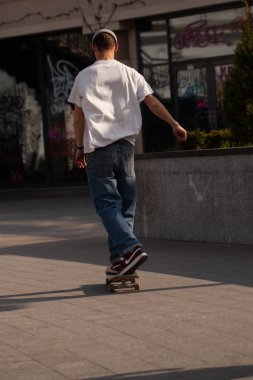 Şık giyinmiş gençler parkta kaykaya biniyorlar..