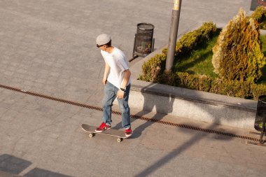 Şık giyinmiş gençler parkta kaykaya biniyorlar..