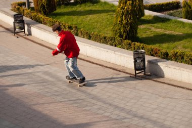 Şık giyinmiş gençler parkta kaykaya biniyorlar..