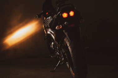 Stüdyodaki gri duvarın arka planında spor siyah motosikleti var..