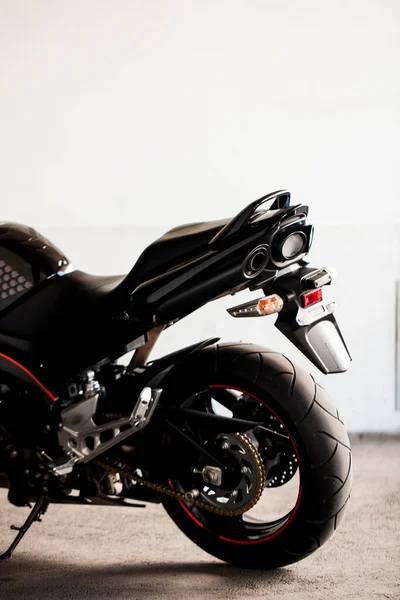 Sports black motorcycle on a background of an underground gray wall in the studio.