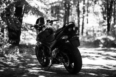 Stüdyodaki gri duvarın arka planında spor siyah motosikleti var..